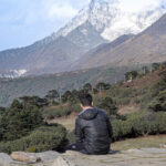 A trekker resting and looking across the Himalayan landscape during a trek through Nepal’s Everest region