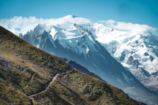 Trekkers walking along an alpine ridge with the snow covered Mont Blanc massif in the background
