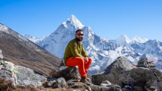 Life Happens Outdoors trekker resting at high altitude with Ama Dablam behind him in Nepal