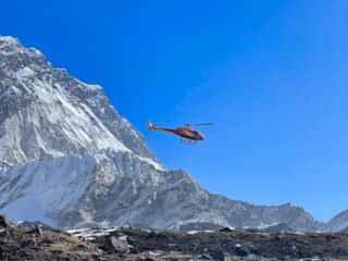 Helicopter flying beside a snow-covered mountain in Nepal's Everest region
