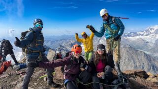 Life Happens Outdoors climbers and guides celebrating on the summit of Weissmies in the Swiss Alps