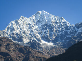 Snow covered Himalayan ridge above dry autumn slopes on a November trek in Nepal