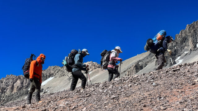 Trekkers ascending a rocky high-altitude slope on Aconcagua during acclimatisation